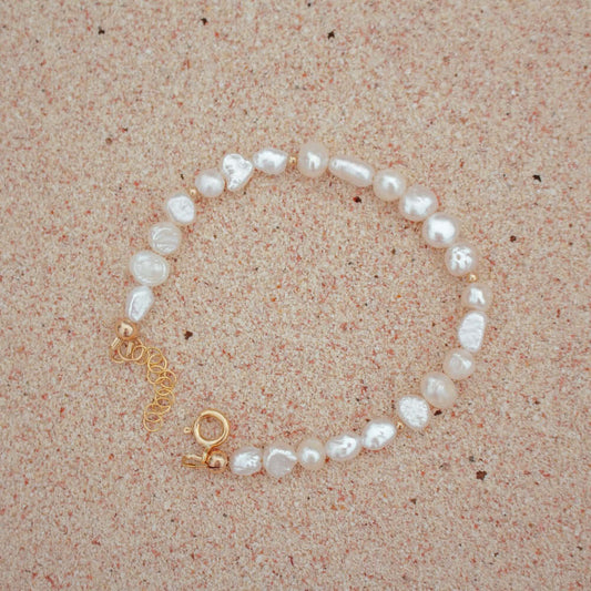 Sand + Salt's freshwater pearl bracelet laying on a sandy beach background, Gold-Filled + Gemstone Jewelry, Sand and Salt Studio