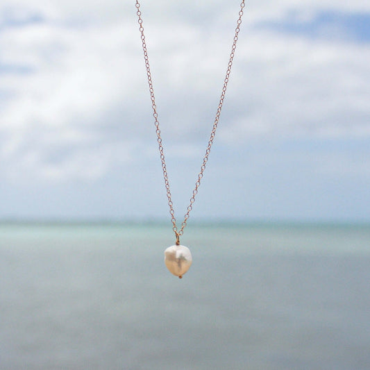 Sand + Salt's pearl pendant necklace, pictured in front of Caribbean water. Gold-filled and gemstone jewelry inspired by coastal living, Sand and Salt Studio