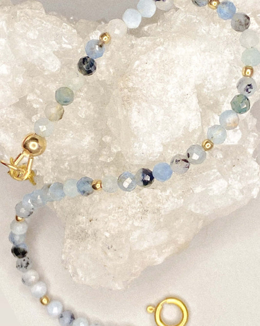 Sand + Salt's aquamarine gemstone bracelet pictured draped on a quartz crystal. Coastal-inspired gemstone and gold filled jewelry, handmade jewelry. Sand and Salt Studio